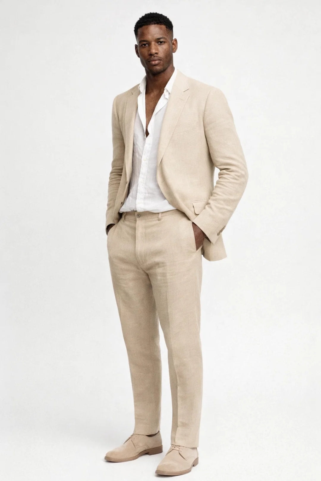 Full-length view of a model in the beige suit with white shirt and suede lace-up shoes, hands in pockets. 3