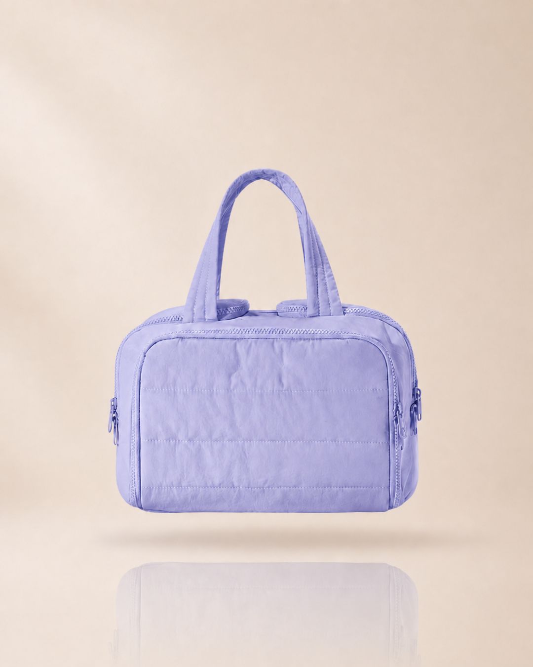 Lilac quilted organiser bag with two handles, front view on a soft beige background with a faint reflection. 15