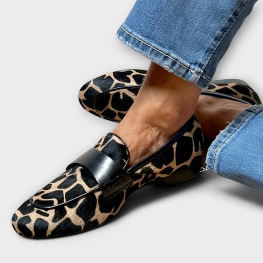 Close-up of the loafers worn with rolled blue jeans, showing the spotted pony-style texture and the black leather strap across the vamp. 2