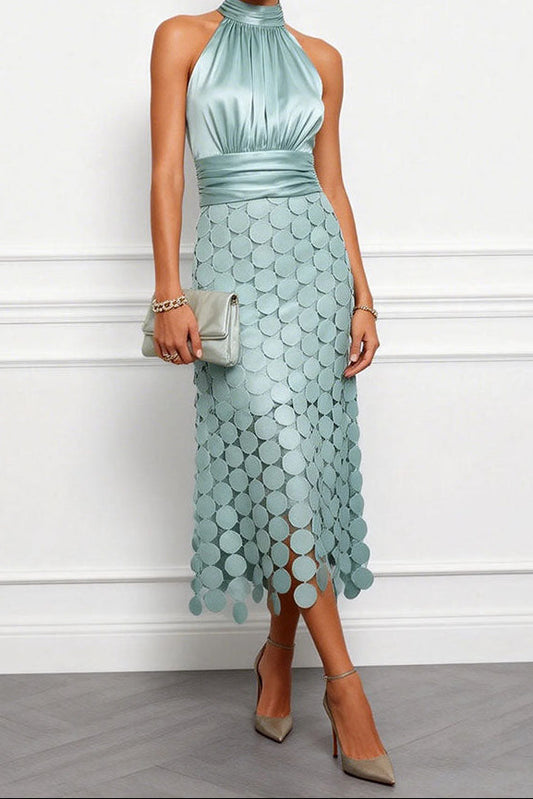Model wears the halter dress in soft sage green with a satin ruched bodice and disc skirt, carrying a pale clutch. 2