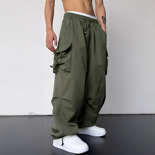 Model wears the baggy cargo trousers in olive green with white trainers, side view 2