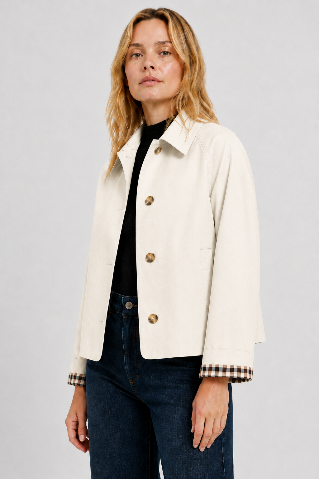 Three-quarter view of the cream jacket worn open over a black top and jeans, showing the turned-back gingham cuffs. 22