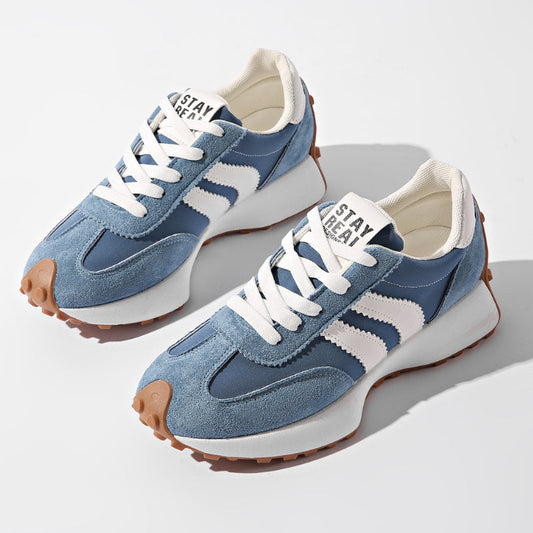 Pair of dusty blue suede trainers with white side stripes and gum soles, photographed from above 2