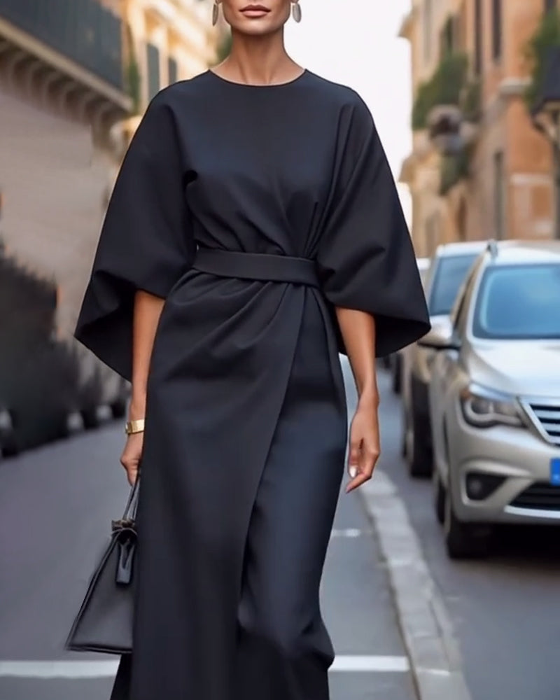 Black wrap-front dress with sleeves flaring at the elbow, worn with drop earrings and a small handbag 6