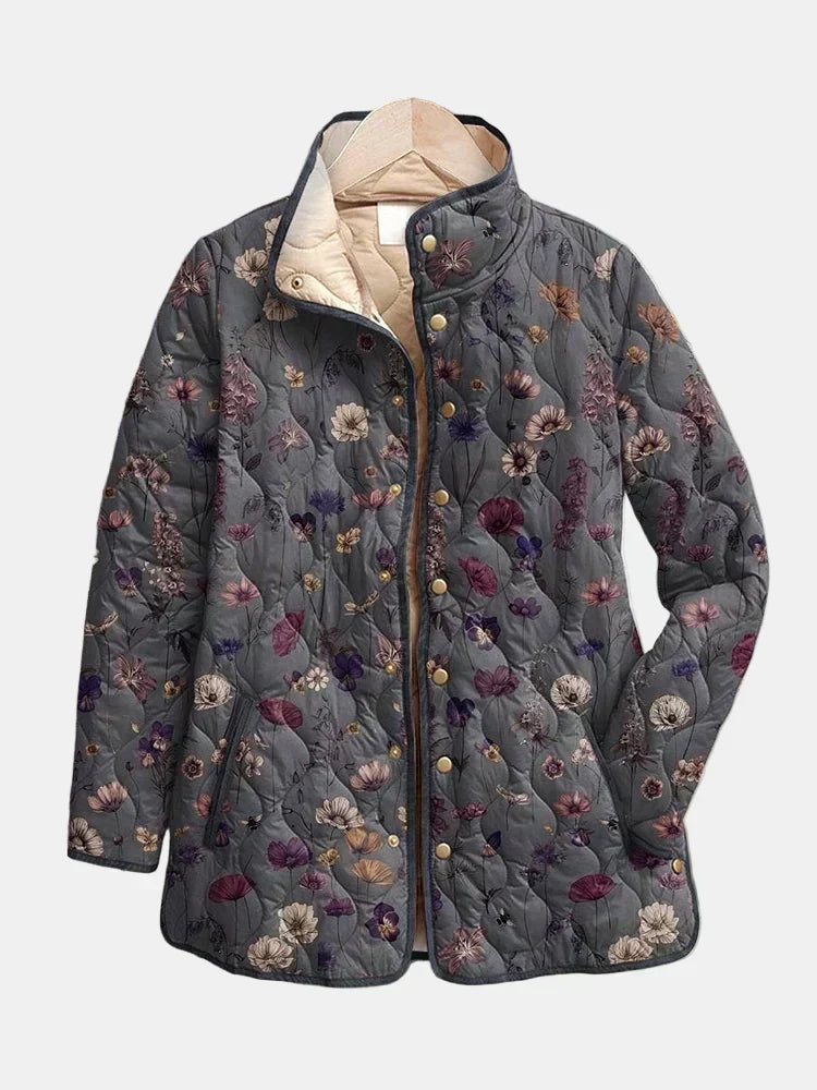 Grey quilted jacket with a purple and pink floral print, gold snap buttons and a cream lining, shown on a hanger. 2