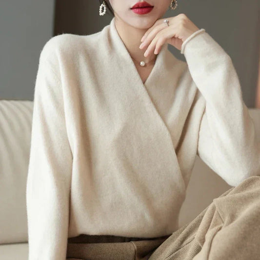 Model in cream wrap-front knit jumper resting her chin on her hand, with brown trousers 2