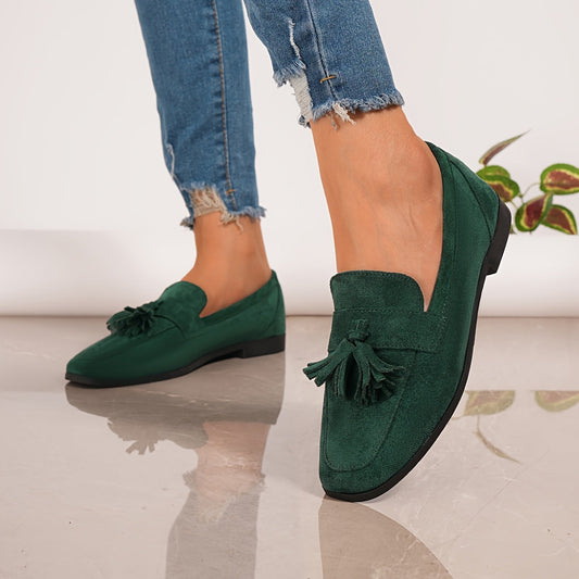 Green tasselled loafers worn with frayed jeans, mid-step on a polished floor 2