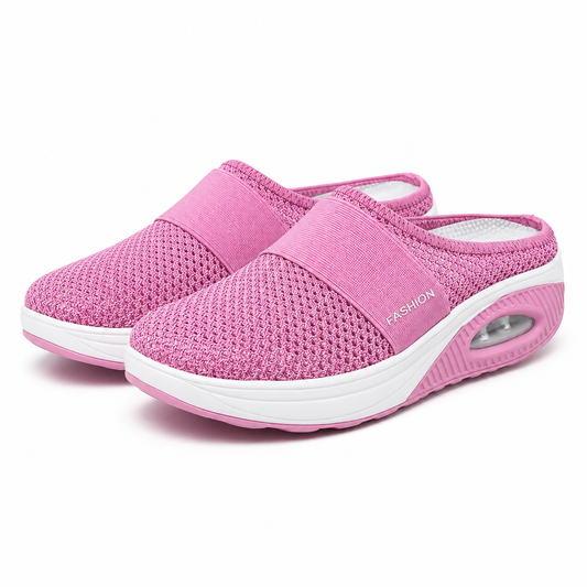 Pair of pink mesh slip-on mules with an elastic strap, white platform sole and a visible air cushion in the heel. 1