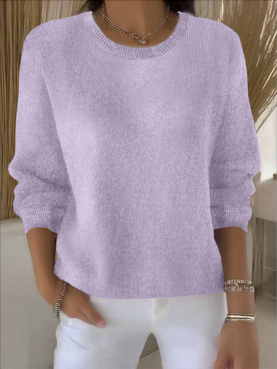 Woman wearing a soft lilac round-neck knit jumper with ribbed neckline, with white trousers 14