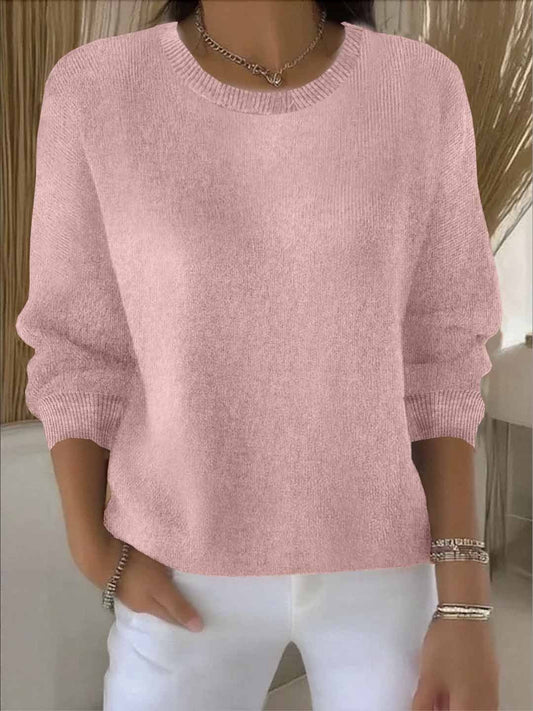 Woman wearing a soft pink round-neck knit jumper with ribbed cuffs, styled with white trousers 2