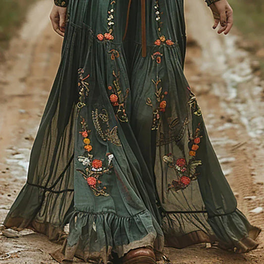 Close-up of the tiered, ruffled skirt hem with orange and cream floral embroidery over sheer panels 2