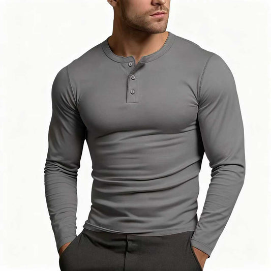 Model wearing the slim-fit long-sleeve Henley in dark grey with a three-button placket, hands in the pockets of dark trousers. 1
