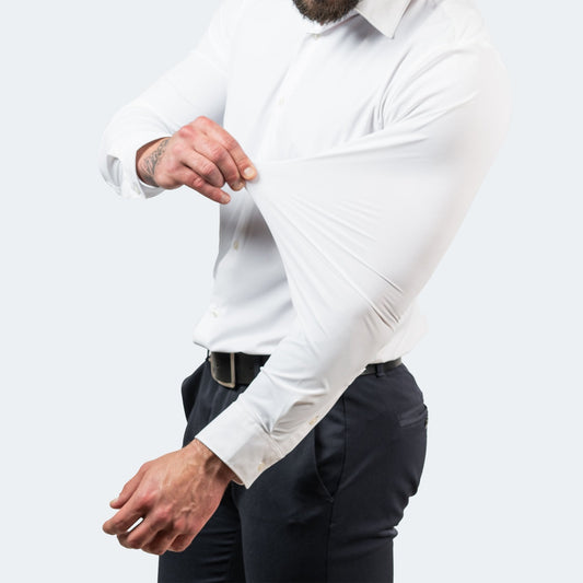 White shirt worn with dark trousers, model pulling the sleeve fabric to show its stretch 2