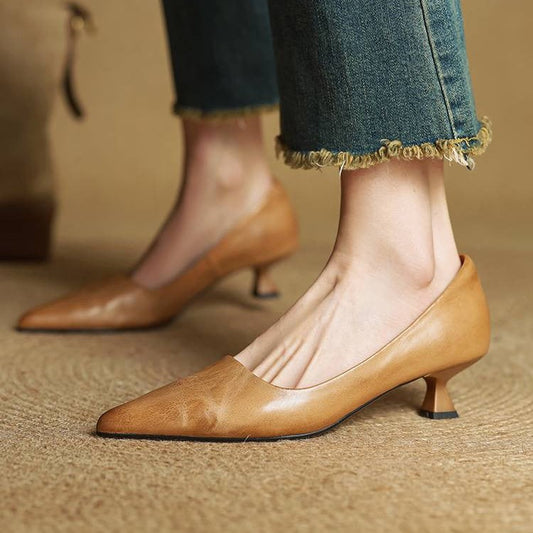 Tan leather kitten heels worn with frayed-hem jeans, seen from the front on woven matting 2