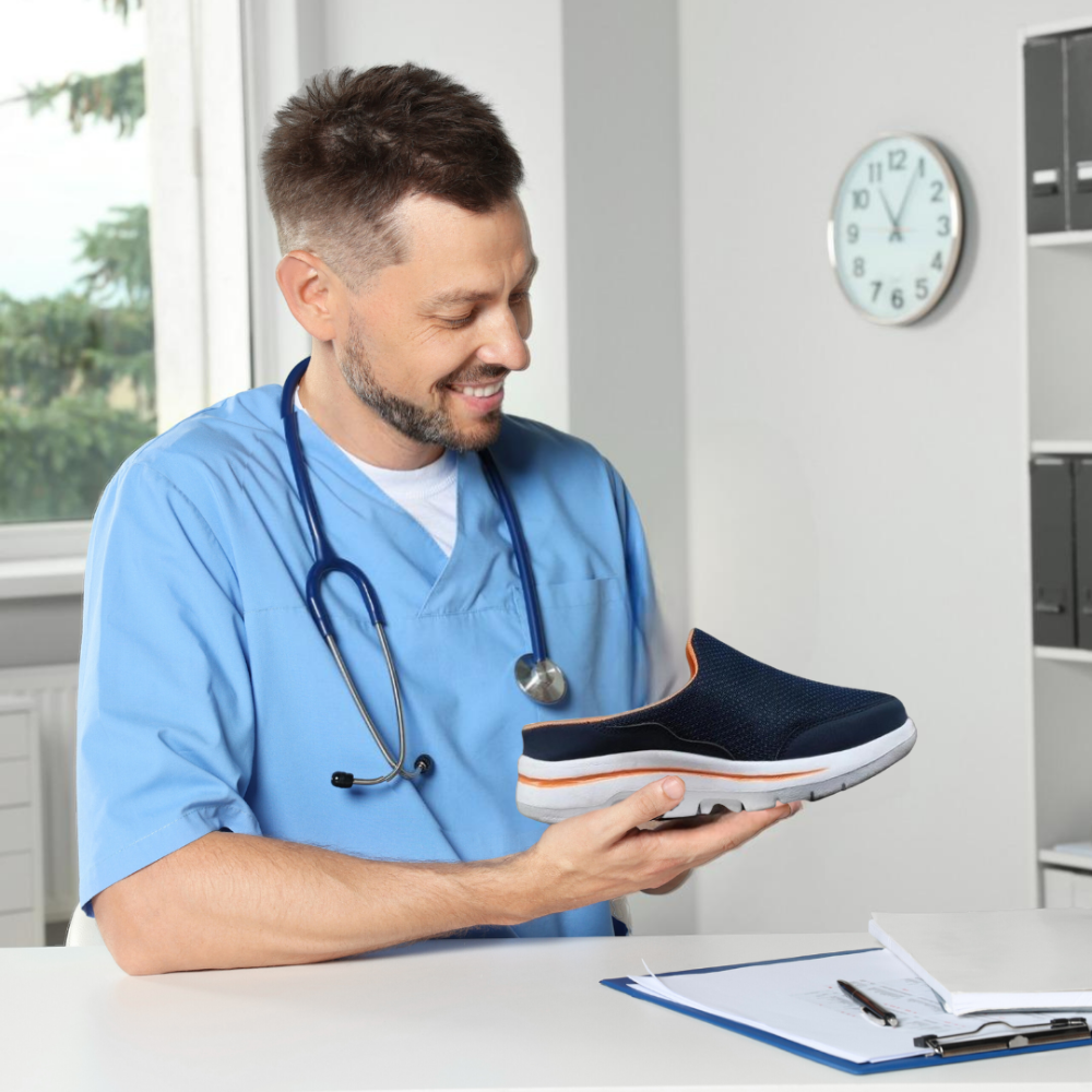 Smiling man in light blue scrubs with a stethoscope examining a navy slip-on with orange trim at a desk. 13