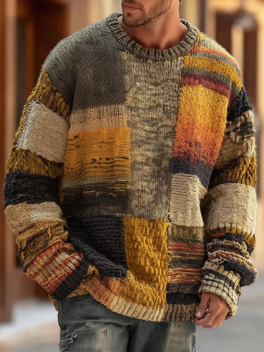 Man wearing the crew-neck sweater outdoors, front view showing mustard, grey, black and cream knitted patchwork panels 1