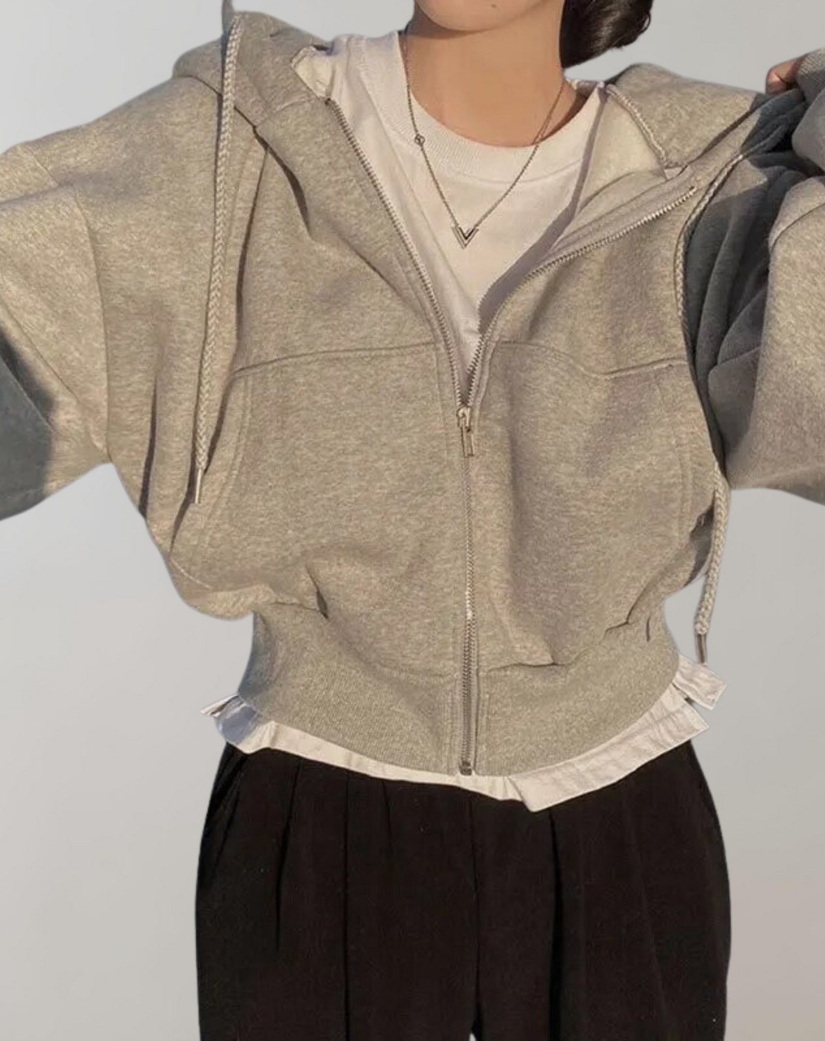 Heather grey zip-up hoodie with ribbed hem, worn open over a white tee and layered shirt hem with black trousers. 5