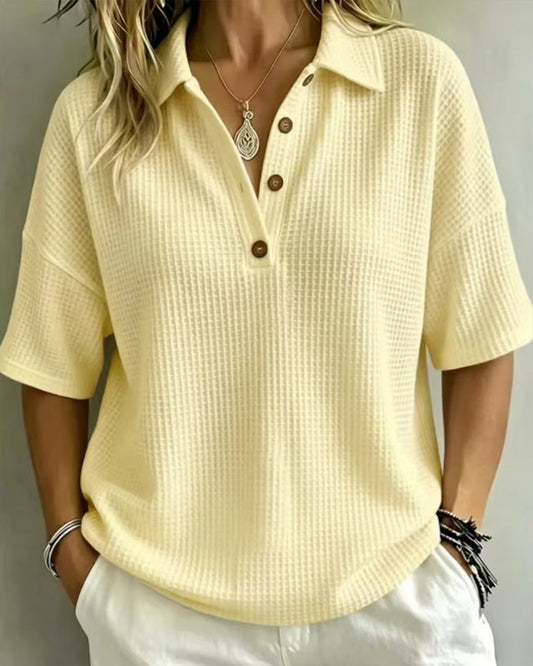 Pale yellow waffle knit polo top with a collar and button placket, worn with white trousers 2