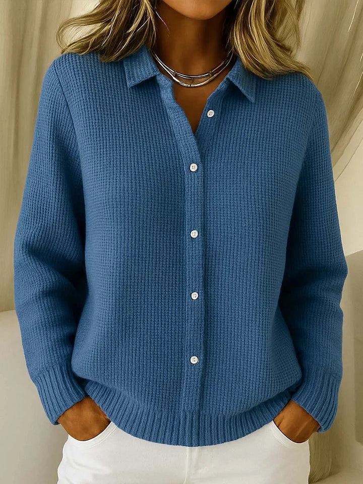 The buttoned polo-style jumper in a medium denim blue, worn by a model with ribbed cuffs and hem visible. 4