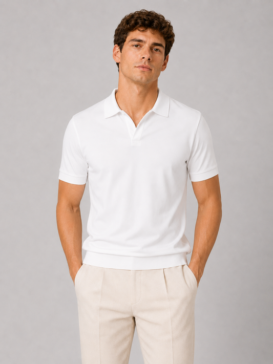 Model in a white short-sleeved polo with an open collar, seen from the front in a close studio shot, worn with cream trousers. 1