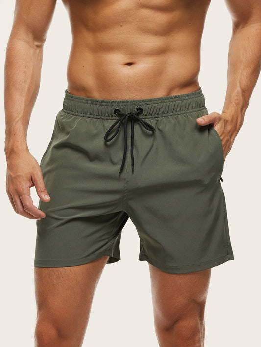 Front view on a model of olive green swim shorts, one hand resting in the side pocket. 2