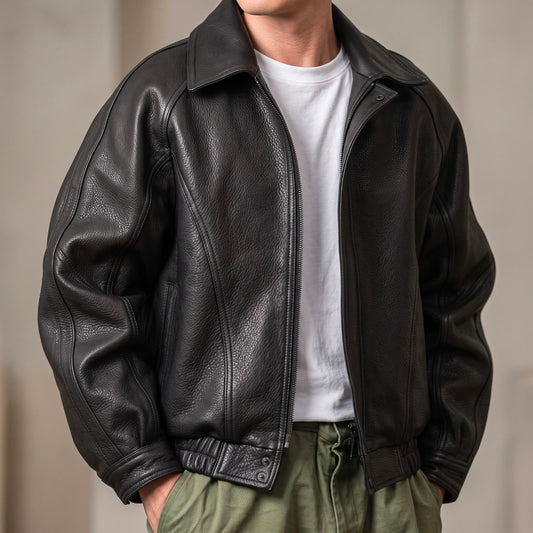 Front view of the black grained leather jacket worn unzipped over a white t-shirt and green trousers, hands in pockets. 1