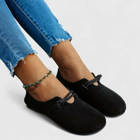 Black suede loafers with rope straps worn with an ankle bracelet and frayed jeans, angled side view 2