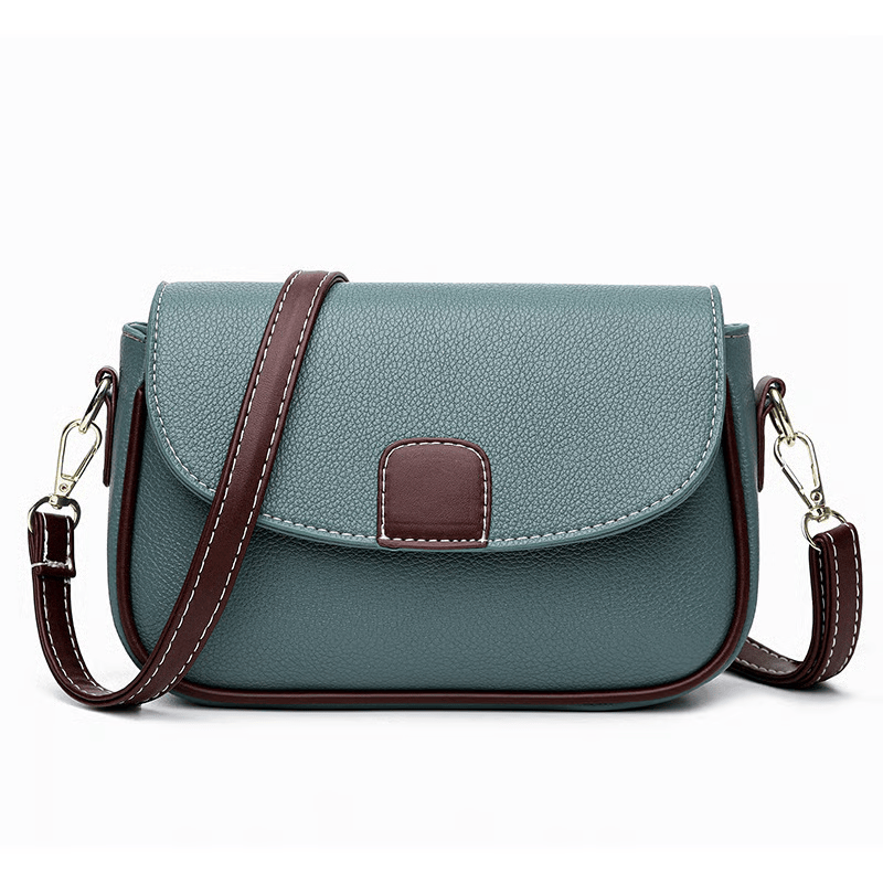 Muted green-blue crossbody bag with brown strap and flap tab, front view on white 8