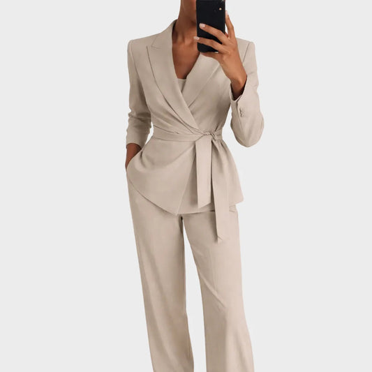Model wearing the beige version of the belted wrap blazer and wide-leg trousers, taking a mirror selfie with a phone. 2