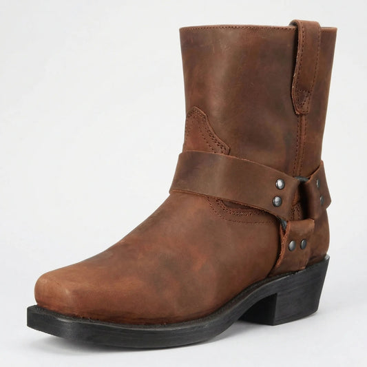 Brown leather mid-calf boot shown from the front corner, with a square toe, riveted harness strap and black heel. 2
