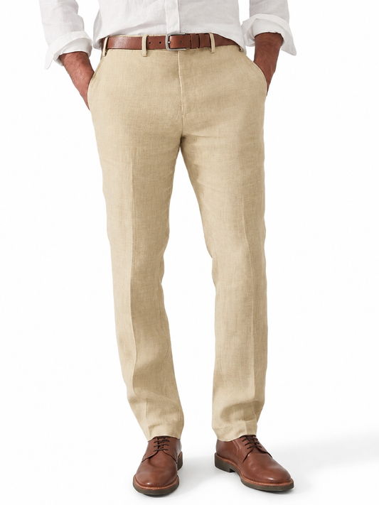 Man wearing sand-coloured linen trousers with a tan leather belt, white shirt and brown lace-up shoes, hands in pockets. 1