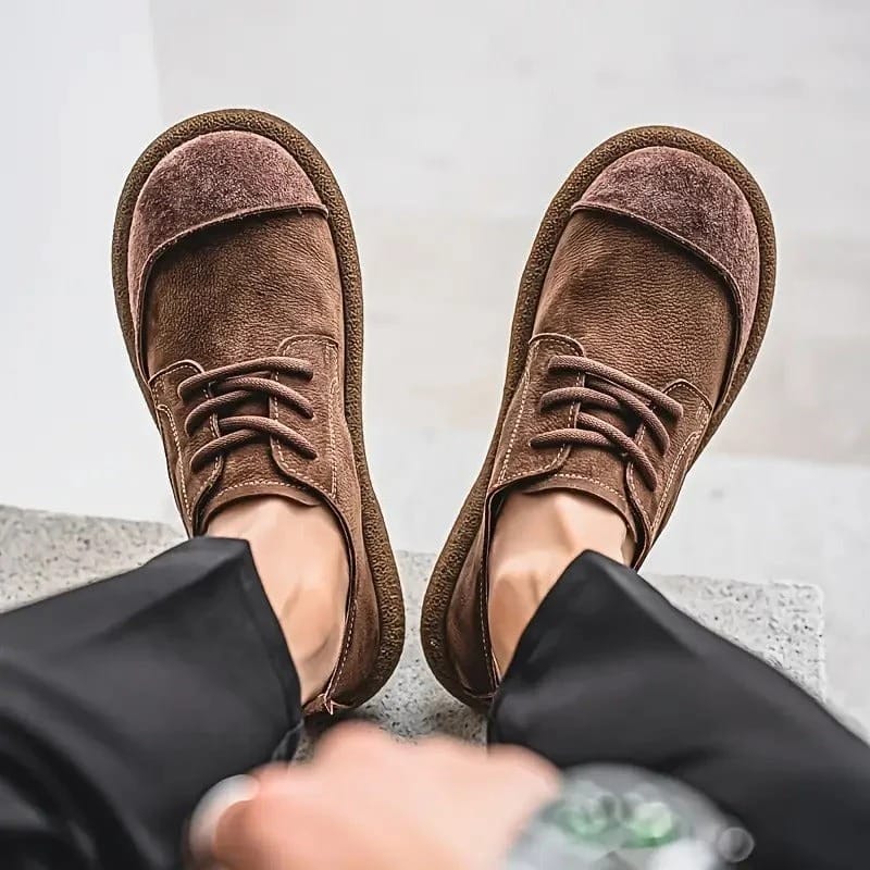 Top-down view of both brown lace-up shoes worn with black trousers on stone steps 12