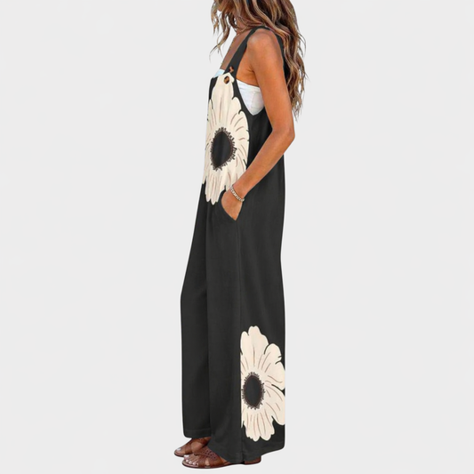 Side view of black wide-leg dungarees on a model, showing cream flowers on the bib and leg 2