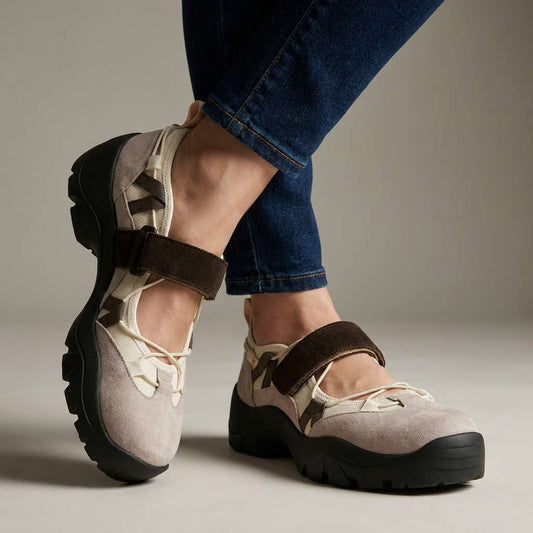 Beige suede shoes with dark brown hook-and-loop straps and chunky black soles, worn with dark skinny jeans against a plain backdrop. 1