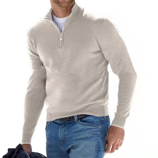 Model walking in the jumper in light beige-grey with a half zip, worn over a white tee and blue jeans. 16