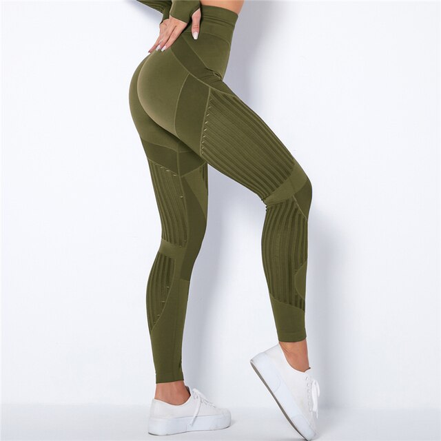 Side view of olive green high-waisted leggings with ribbed mesh panels, model's hand resting on hip 5