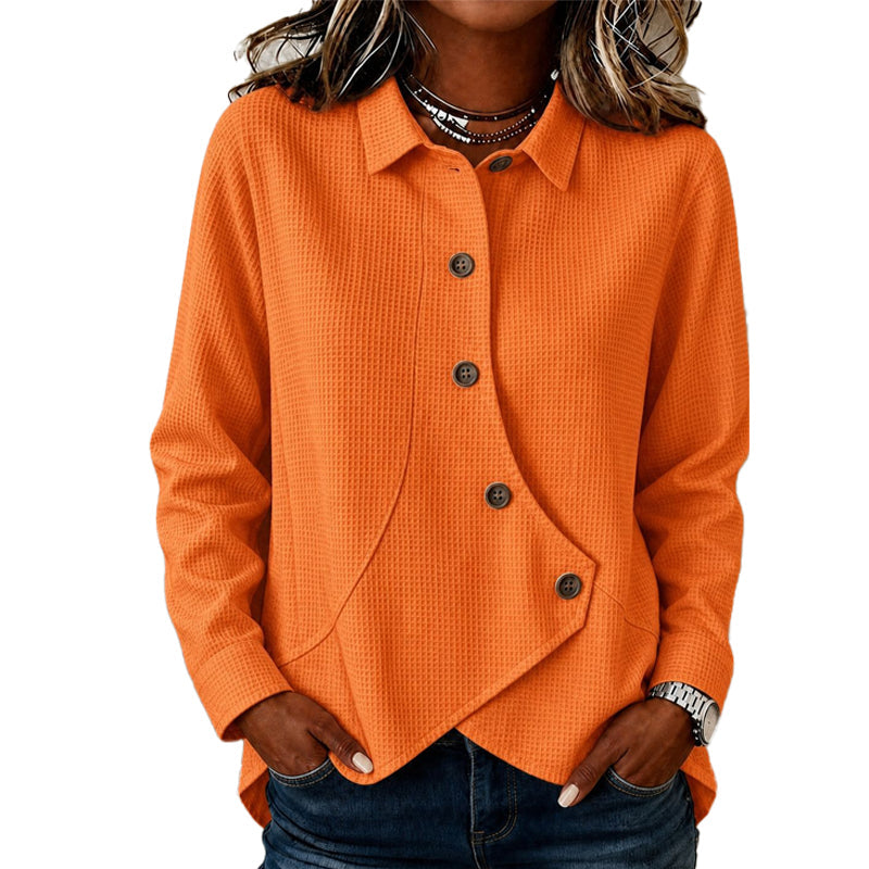 Model wearing the waffle-knit top in orange, hands in jeans pockets, showing the collar, brown buttons and curved asymmetric hem. 4
