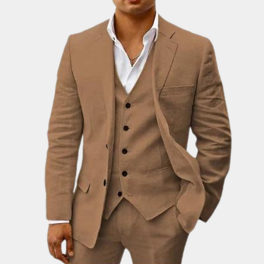 Model wearing the suit in a camel-brown colour, with the jacket open over the vest and one hand in a pocket. 2
