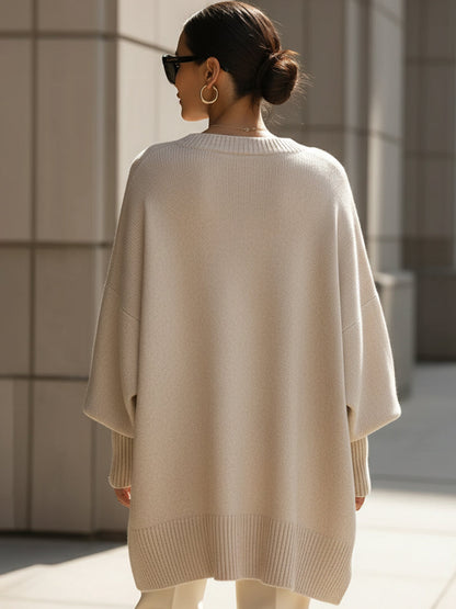 Back view of the beige knit poncho, showing the loose drape and ribbed hem 5