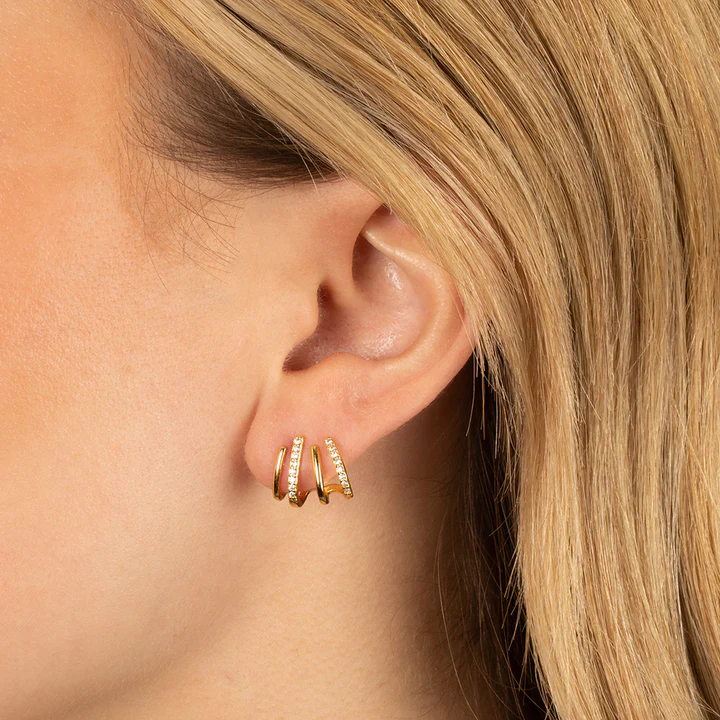 Close-up of a blonde woman's ear wearing the gold earring, two of its bands set with stones 4