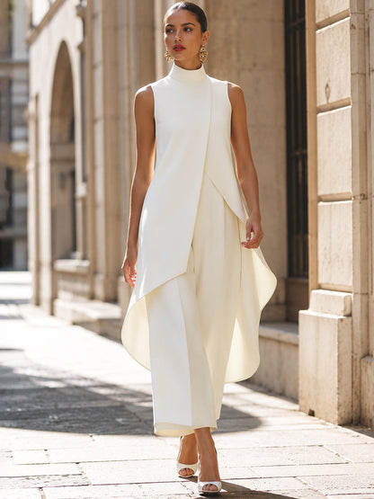 Model in the cream set walks along a sunlit stone street, the curved hem of the top swaying over the trousers. 9