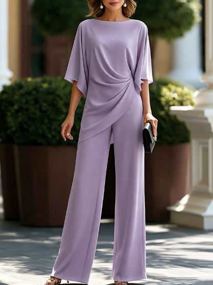 Model standing outdoors in the set in soft lilac, with a draped batwing-sleeve blouse and wide-leg trousers. 6