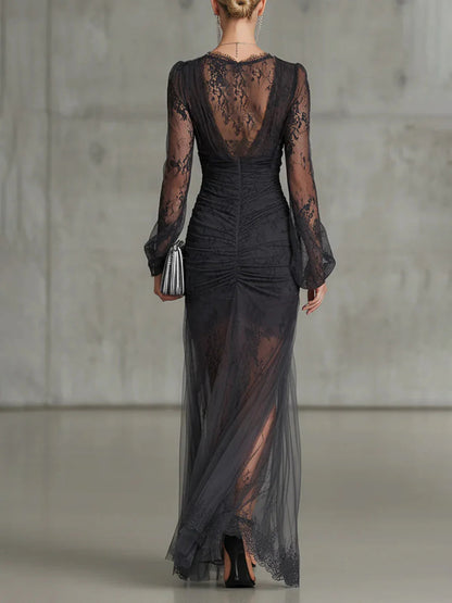 Back view of the black lace maxi dress on a model, showing the sheer lace back, ruched waist and tulle skirt. 2