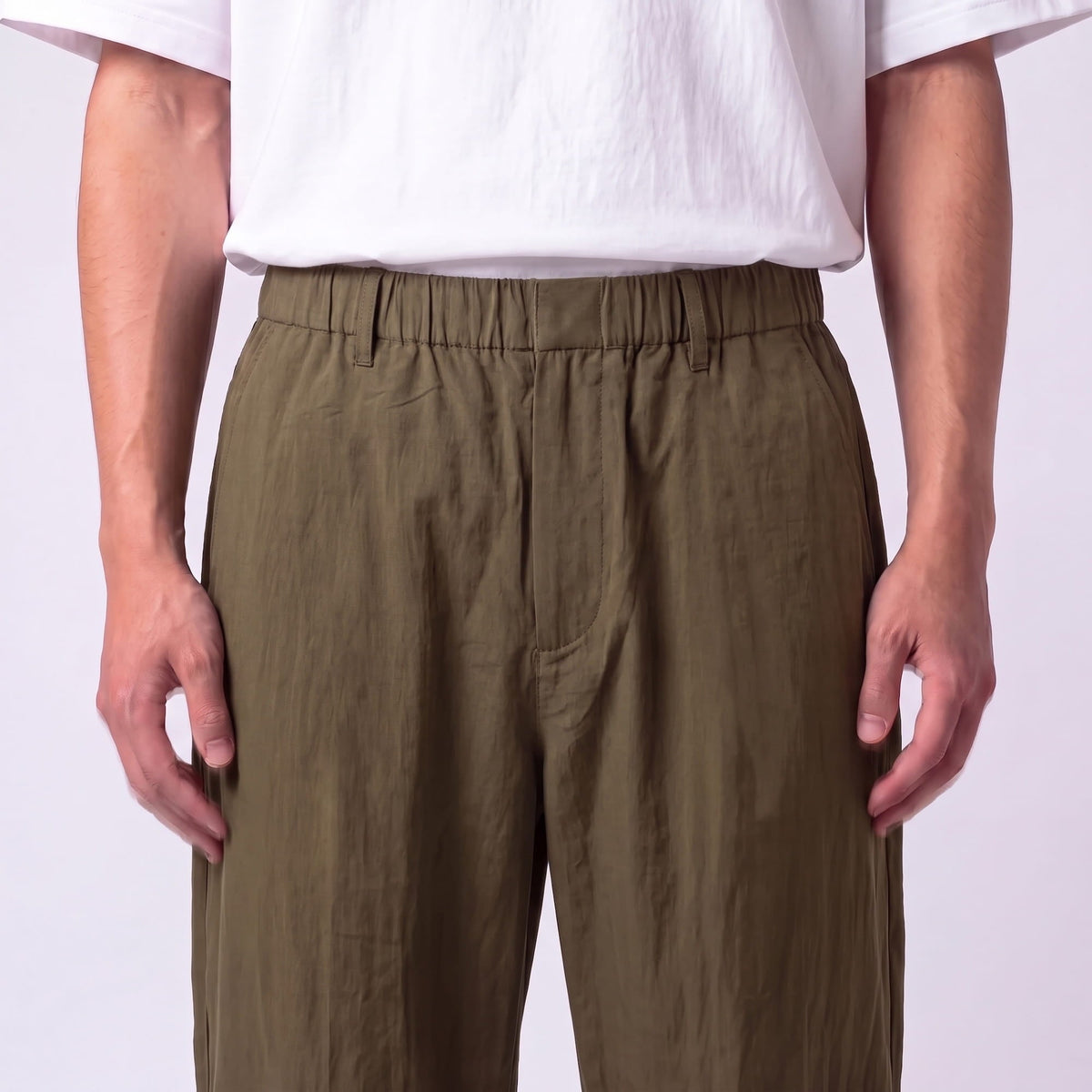 Close-up of the olive green waistband, showing the elasticated waist, belt loops, flat front fly and creased fabric texture. 11