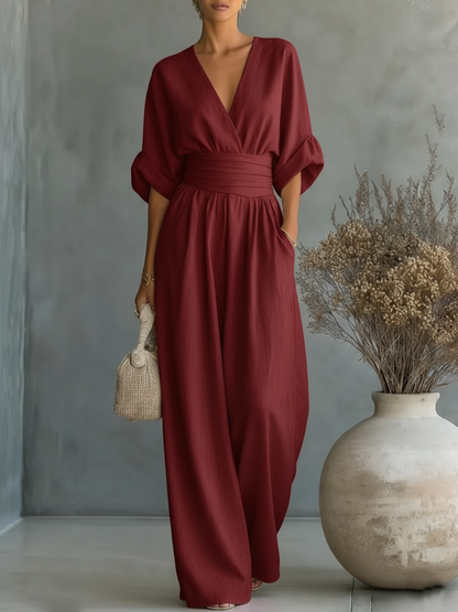 Burgundy jumpsuit on a model, showing the wrap-style V-neck, wide waist band and long flowing wide-leg trousers 9