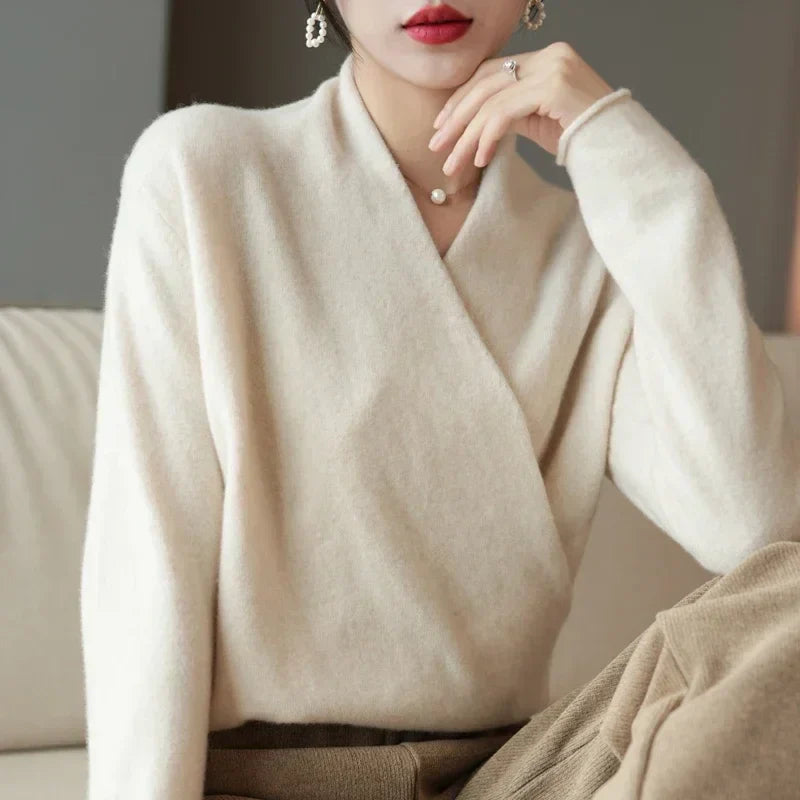 Cream wrap jumper on a seated model with her hand raised to her chin 14