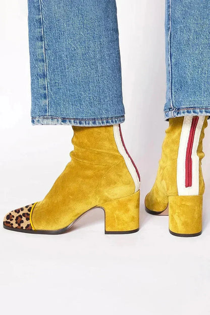Mustard yellow suede ankle boots with a leopard-print toe cap and cream back panel with red zip, worn with jeans. 5