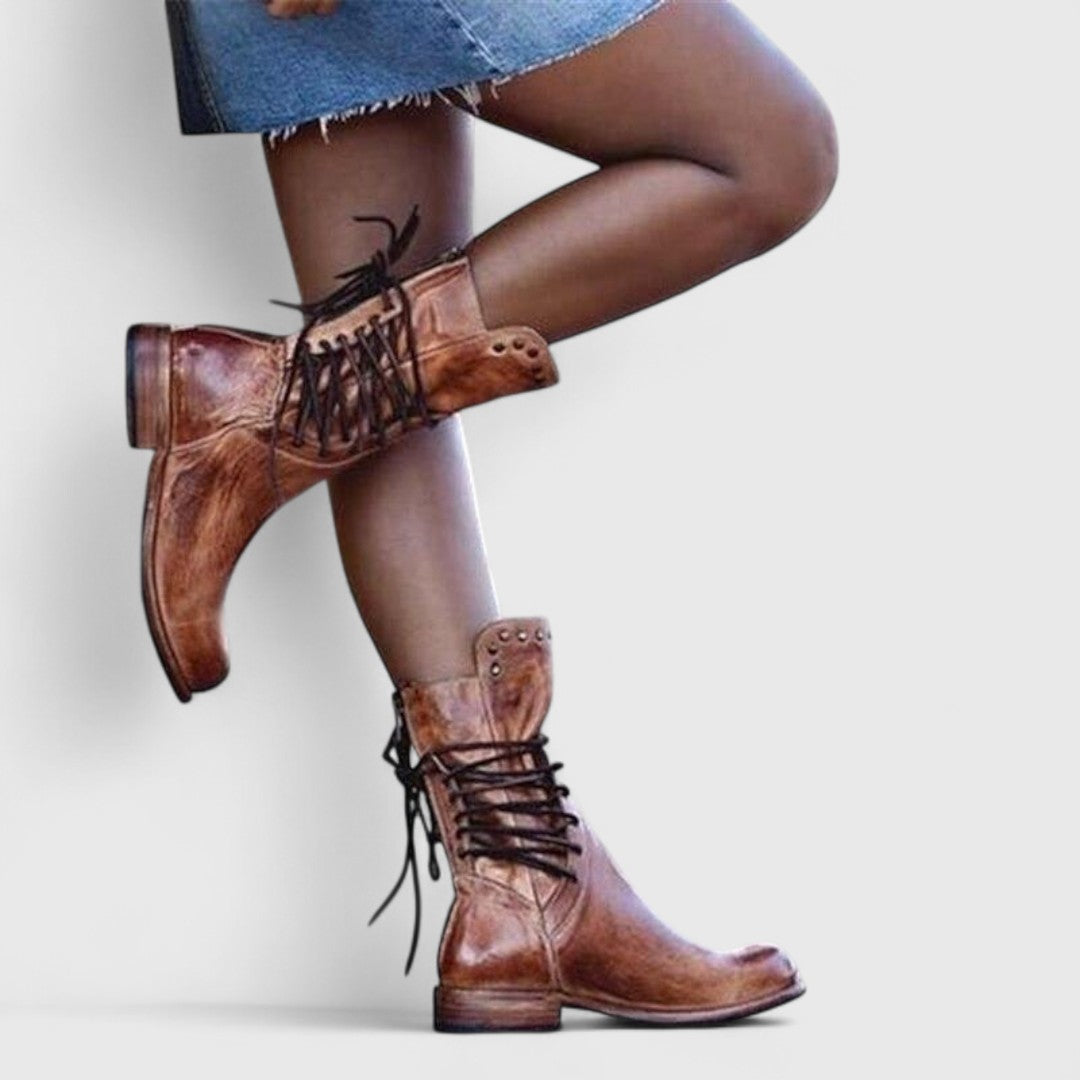 Model in a denim skirt and brown leather lace-up boots, standing with one knee bent against a pale wall. 9
