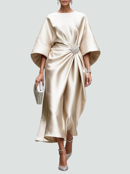 Model wearing the satin dress in pale champagne, with cape-style sleeves, a draped waist brooch and sparkling earrings, clutch and shoes. 6