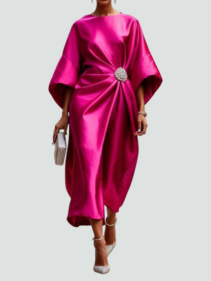 Model wearing the satin dress in vivid fuchsia pink, with voluminous sleeves, gathered waist brooch, jewelled clutch and sparkly heels. 4